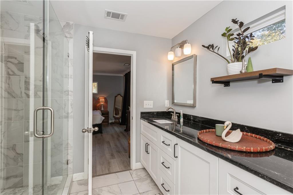 1184 Metropolitan Parkway Southwest Atlanta, GA 30310 - Photo 15 of 26 a bathroom with a granite countertop sink a mirror and shower