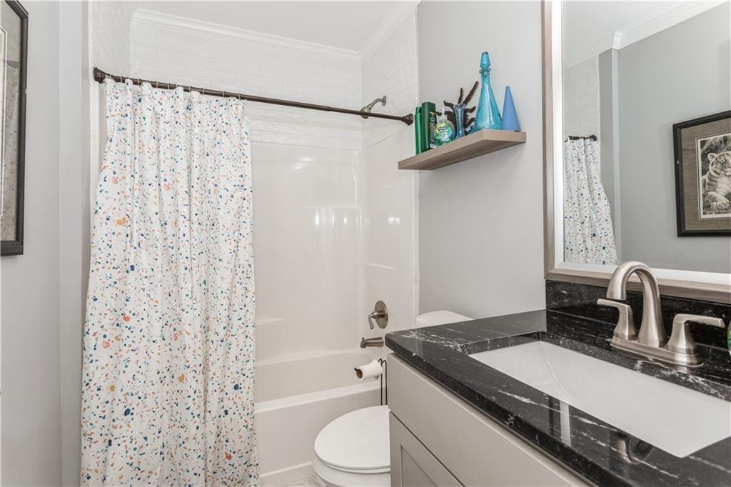 1184 Metropolitan Parkway Southwest Atlanta, GA 30310 - Photo 17 of 26 a bathroom with a granite countertop sink toilet a mirror a bathtub and shower