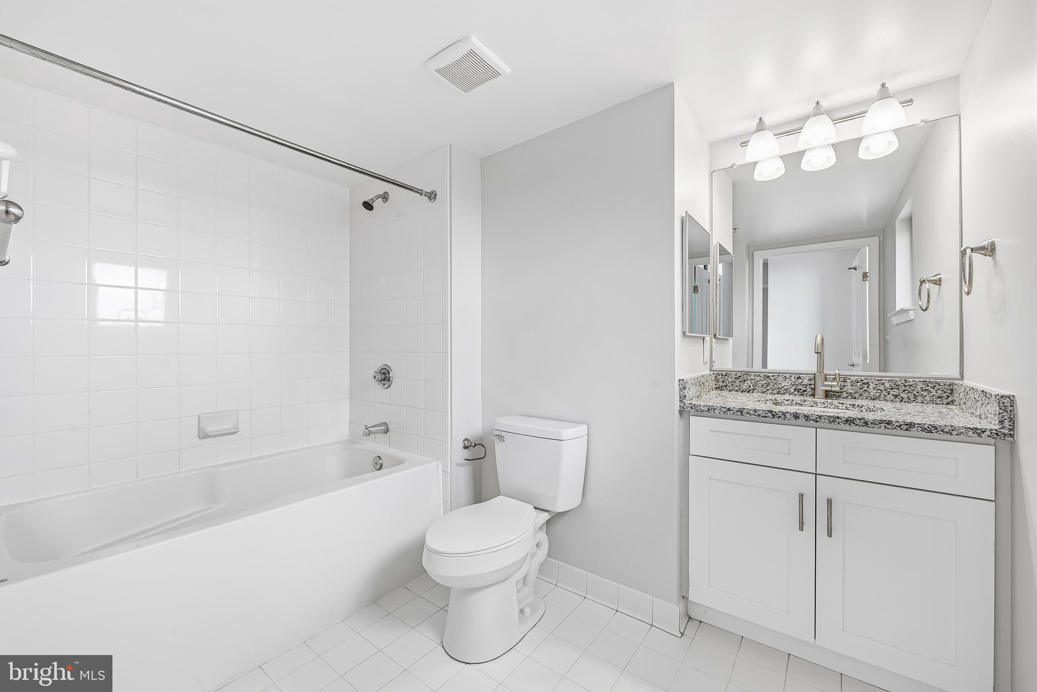 414 Water Street, Unit 1501 Baltimore, MD 21202 - Photo 26 of 35 a bathroom with a granite countertop sink a toilet mirror and shower