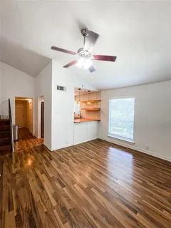 a view of empty room with wooden floor and fan