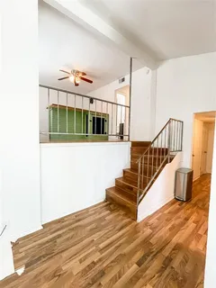 an empty room with wooden floor fan and windows