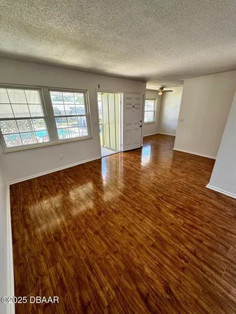an empty room with wooden floor and windows