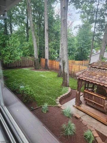 a view of a backyard with wooden fence and a trees