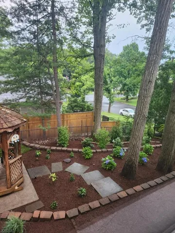 a view of a backyard with table and chairs potted plants and large tree