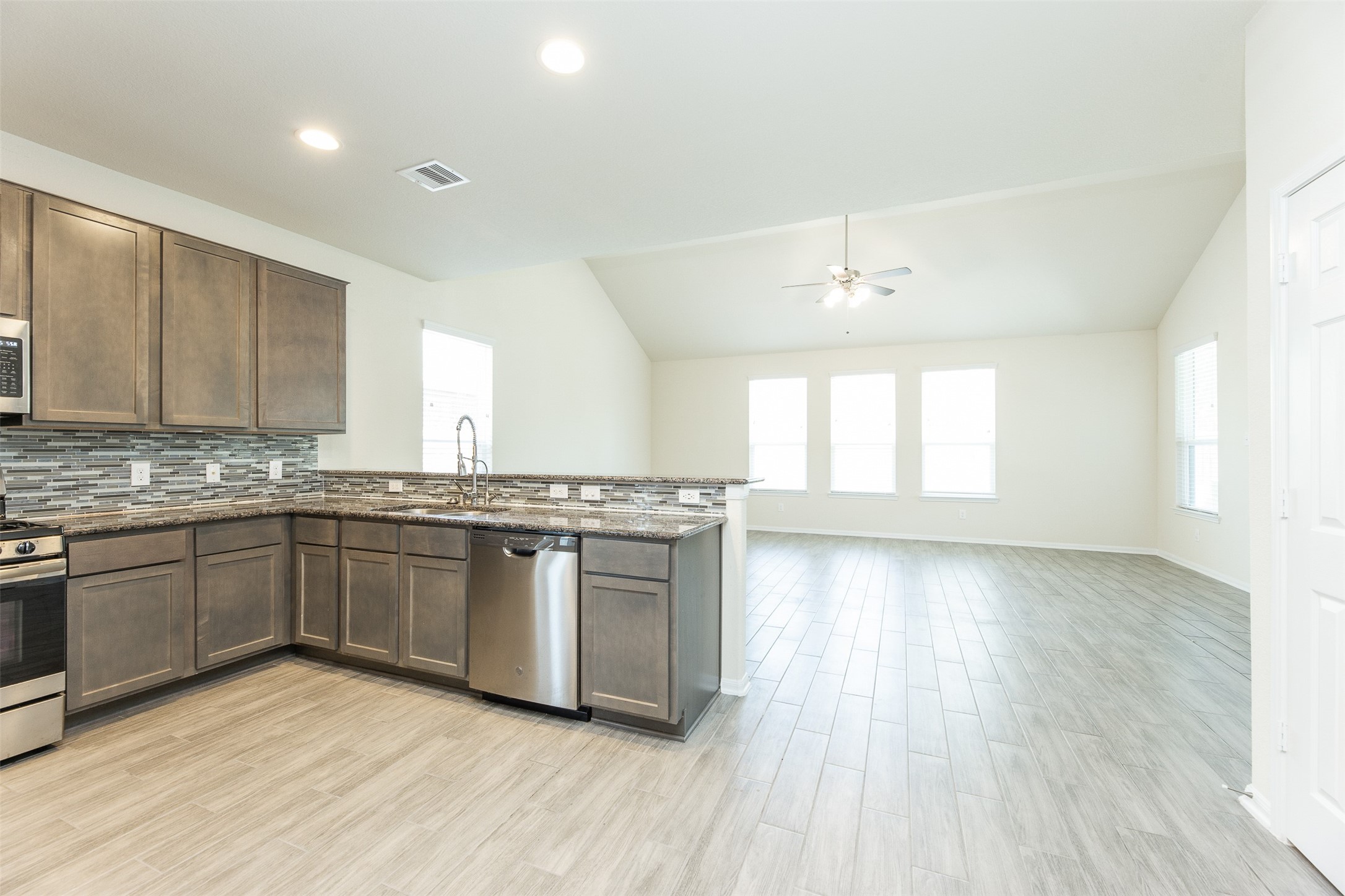 2293 Garden Square Path Spring, TX 77386 - Photo 13 of 32 a large kitchen with granite countertop a stove top oven a sink and dishwasher with wooden floor
