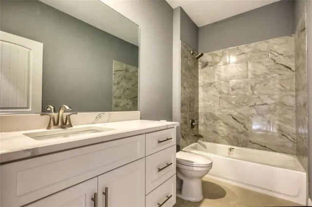 a bathroom with a granite countertop sink toilet mirror and bathtub