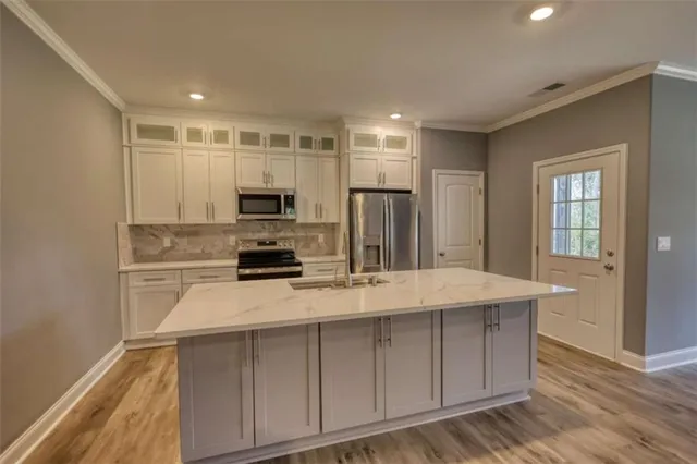 a kitchen with a sink a microwave a refrigerator and cabinets