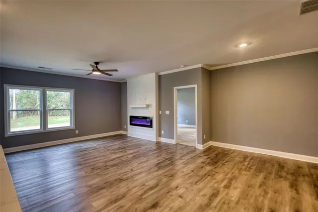 a view of an empty room with window and wooden floor