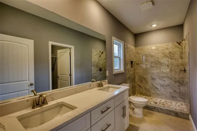 a bathroom with a granite countertop sink a toilet and shower
