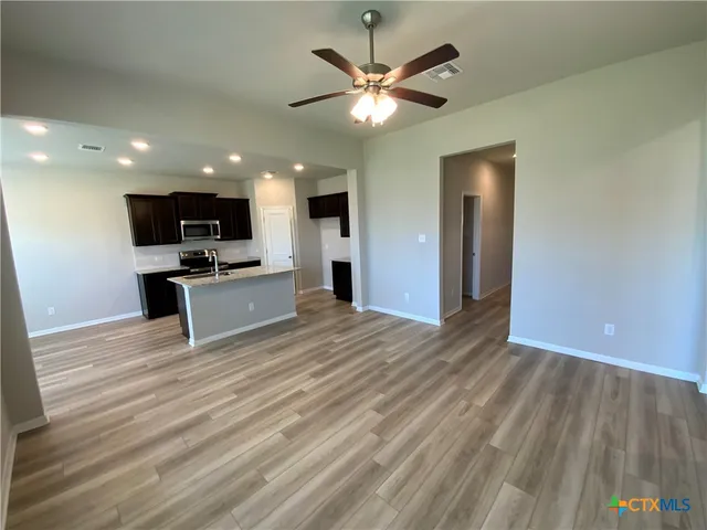 a view of a kitchen with a sink a ceiling fan and wooden floor