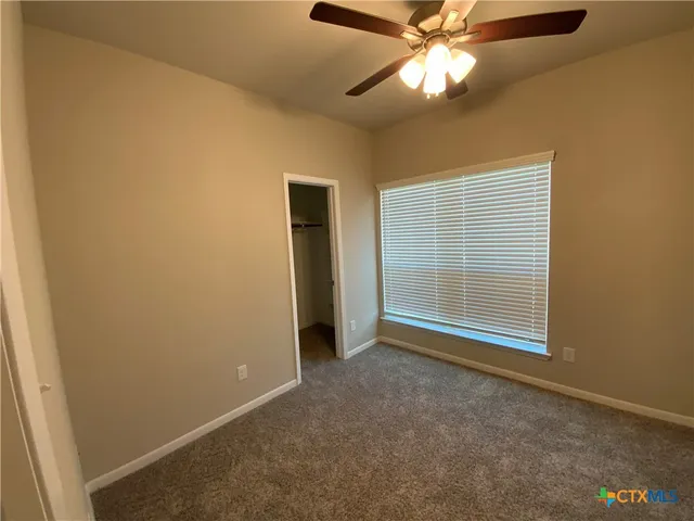 an empty room with a ceiling fan and a window