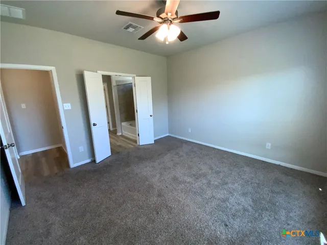 an empty room with closet and a chandelier fan