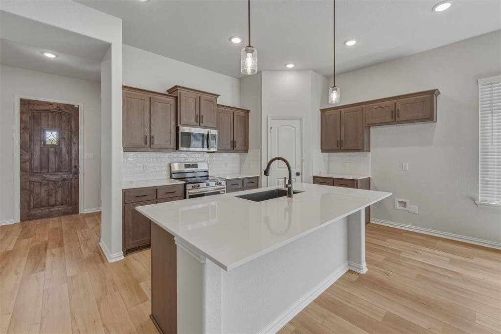 1213 Colca Drive Springtown, TX 76082 - Photo 7 of 23 Kitchen featuring a center island with sink, white countertops, stainless steel appliances, subway tile backsplash, and recessed lighting