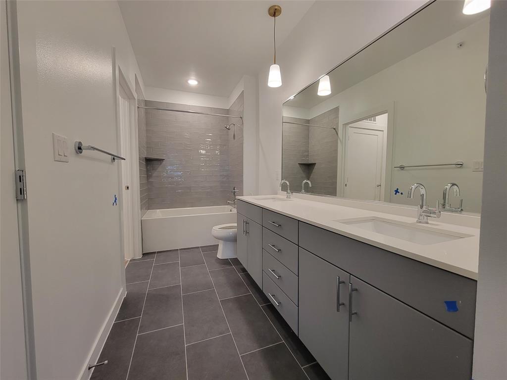 4801 Springdale Road, Unit 2211 Austin, TX 78723 - Photo 12 of 19 A well-lit primary bathroom features a double vanity and a shower-tub combination with sleek tile.