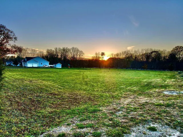 a view of a golf ground with huge green field and large trees