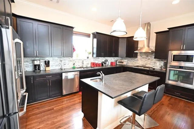 a kitchen with stainless steel appliances granite countertop a sink dishwasher stove refrigerator and cabinets