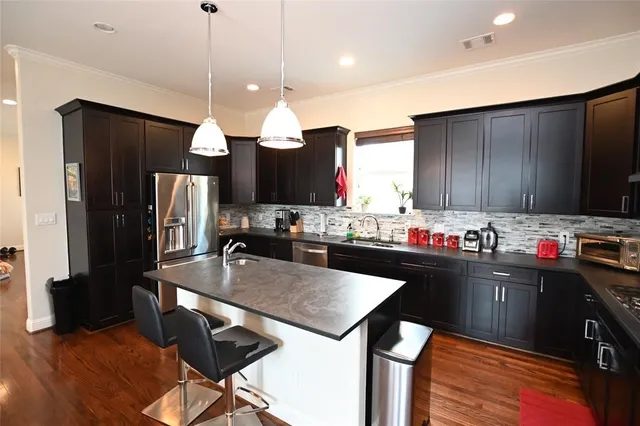 a kitchen with kitchen island granite countertop a sink refrigerator and cabinets