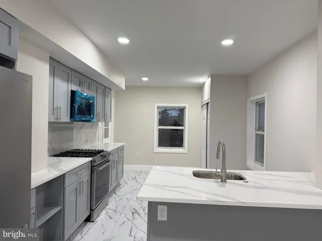 a kitchen with kitchen island granite countertop a sink and a stove top oven with wooden floor