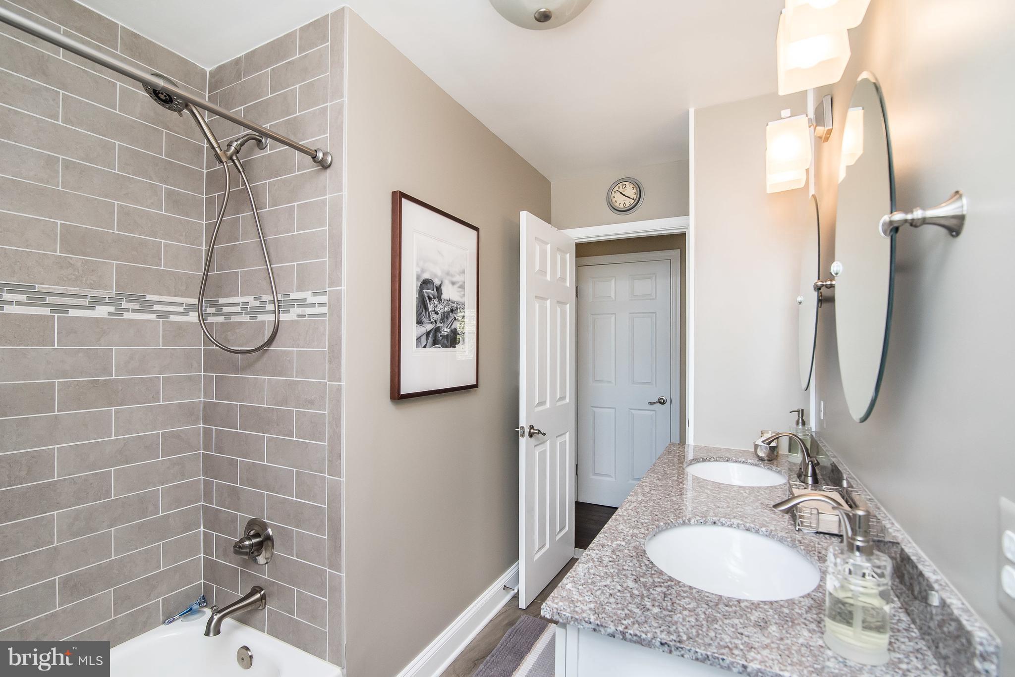 4042 High Point Road Ellicott City, MD 21042 - Photo 17 of 29 a bathroom with a granite countertop sink a mirror and shower