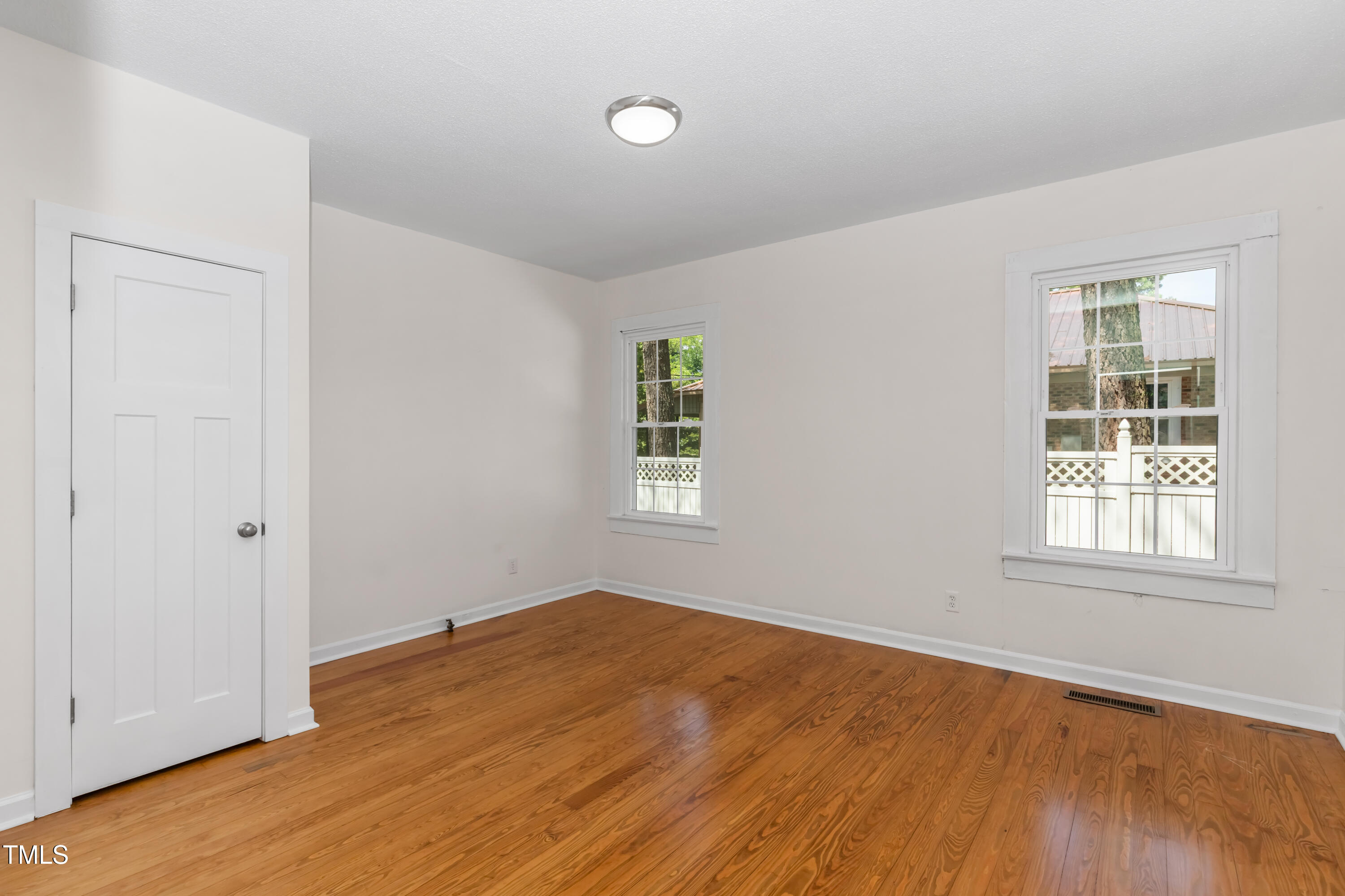 726 West M Street Erwin, NC 28339 - Photo 5 of 26 an empty room with wooden floor and windows