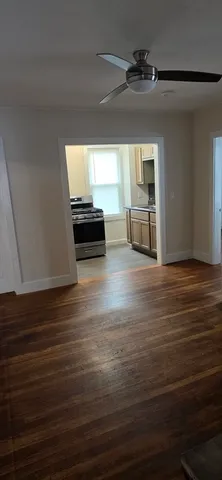 a view of empty room with wooden floor and fan