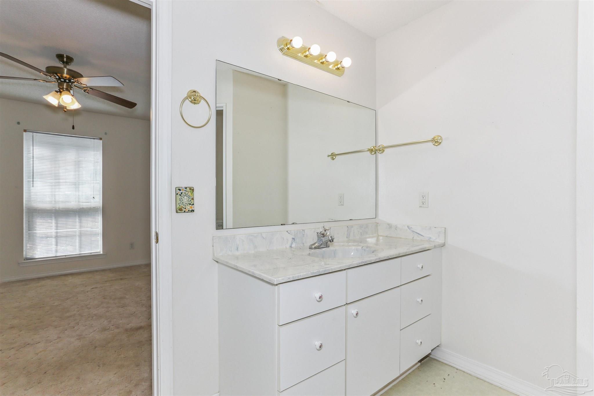939 Avalon Boulevard Milton, FL 32583 - Photo 40 of 56 a bathroom with a granite countertop sink a light fixture and a mirror