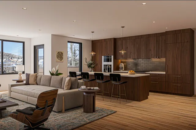 a living room with couches kitchen view and wooden floor