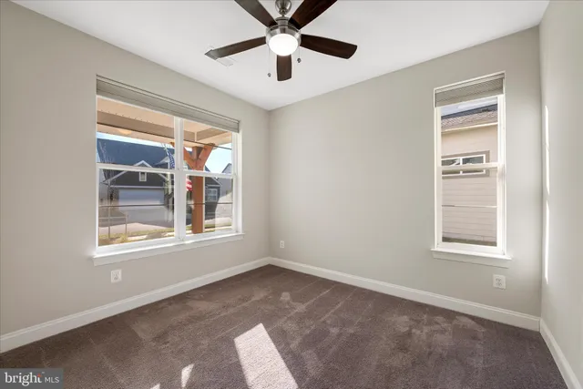 a view of an empty room with a window and a ceiling fan