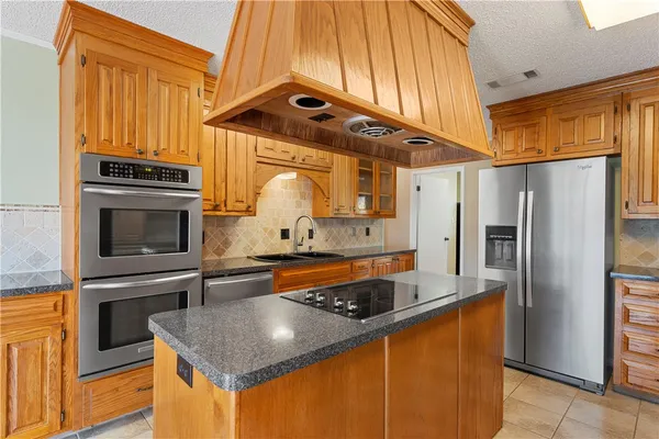 a kitchen with stainless steel appliances granite countertop a refrigerator a stove and a sink
