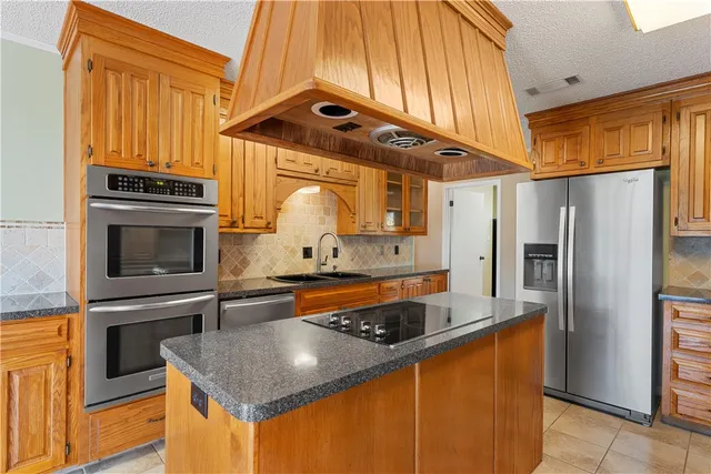 a kitchen with stainless steel appliances granite countertop a refrigerator a stove and a sink