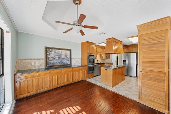 a kitchen with stainless steel appliances wooden floor and a refrigerator