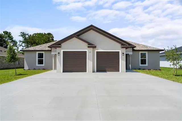 front view of house with a yard and trees