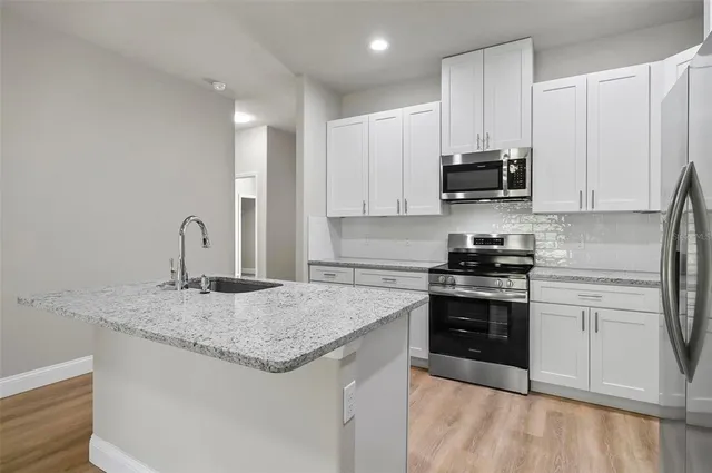 a kitchen with stainless steel appliances granite countertop a sink stove and refrigerator