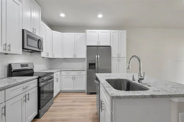 a kitchen with stainless steel appliances granite countertop a sink a stove and a refrigerator