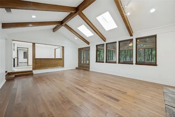 a view of an empty room with a window and wooden floor