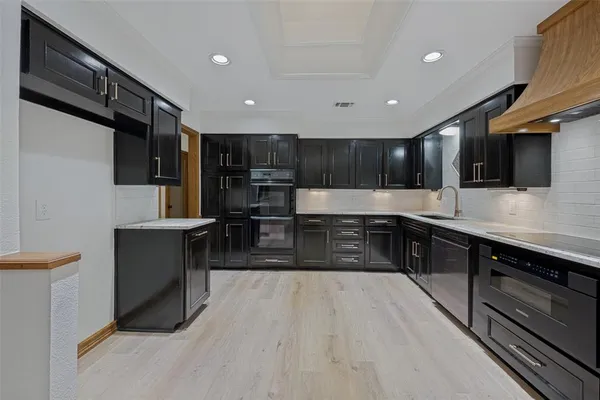 a large kitchen with stainless steel appliances wooden cabinets and a stove top oven