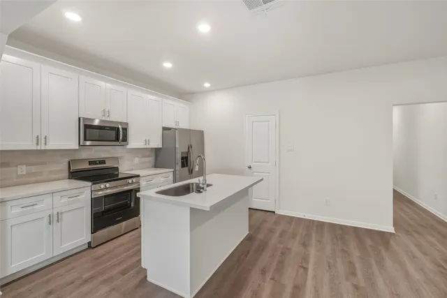 a kitchen with a sink stainless steel appliances and white cabinets