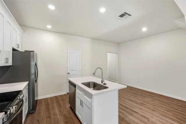 a kitchen that has a sink and a stove with wooden floor