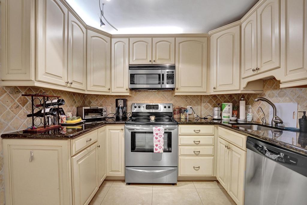 2000 South Ocean Boulevard, Unit 4C Lauderdale-by-the-Sea, FL 33062 - Photo 17 of 49 a kitchen with white cabinets and stainless steel appliances