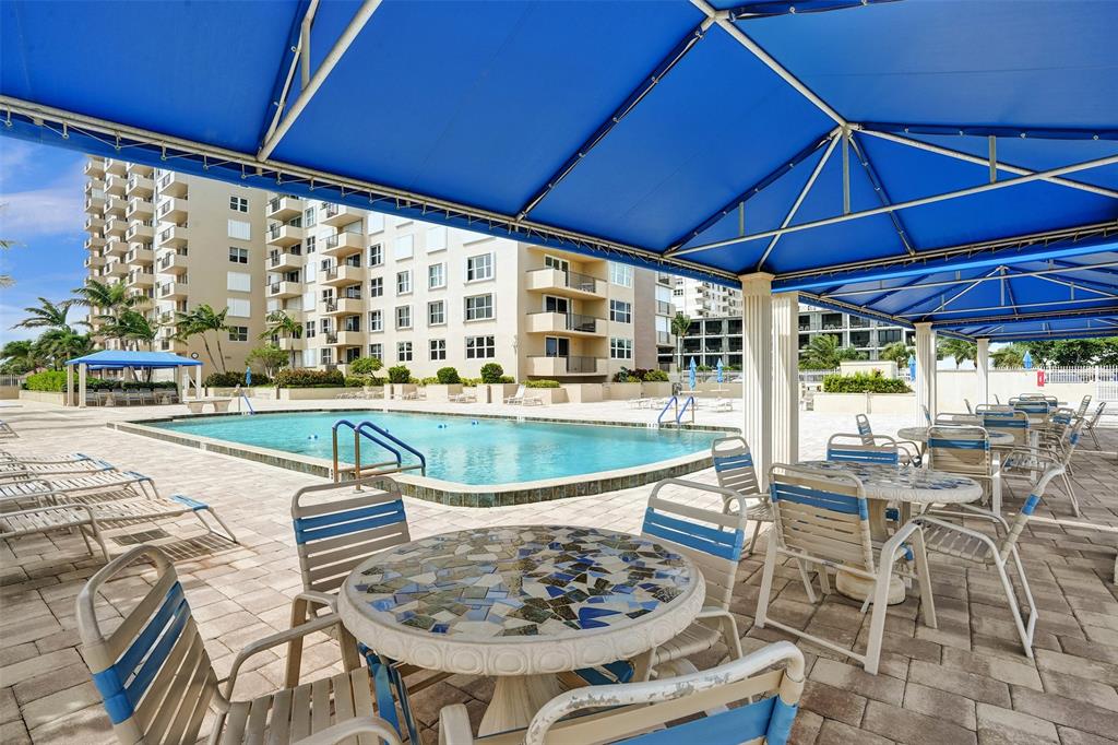 2000 South Ocean Boulevard, Unit 4C Lauderdale-by-the-Sea, FL 33062 - Photo 38 of 49 a view of a swimming pool with a table and chairs under an umbrella