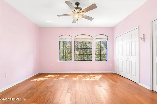 an empty room with a window and ceiling fan