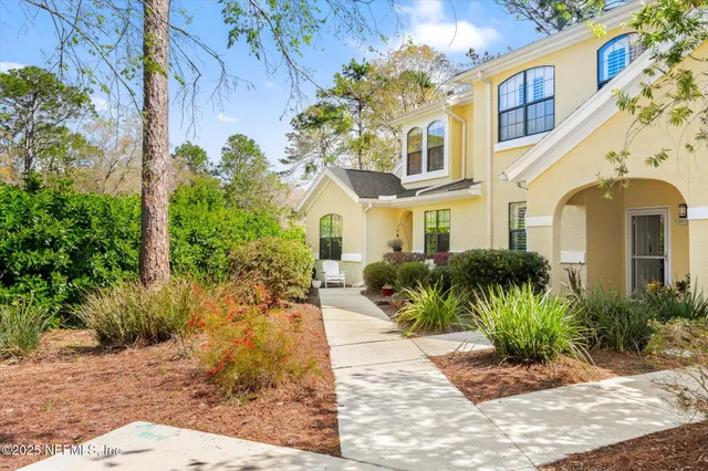 a front view of a multi story residential apartment building with yard and bench