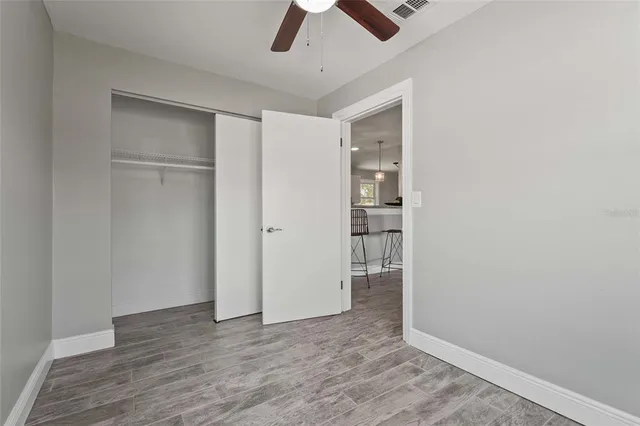 an empty room with closet and a chandelier fan