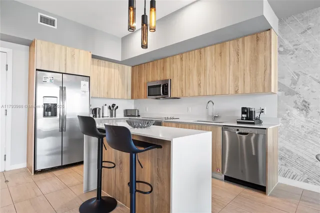 a kitchen with stainless steel appliances granite countertop a refrigerator a sink a stove and white cabinets with wooden floor