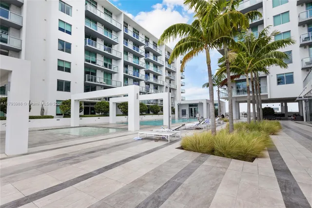 a view of a swimming pool with a lawn chairs and palm trees