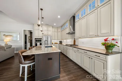 a kitchen with kitchen island granite countertop a table chairs sink and cabinets