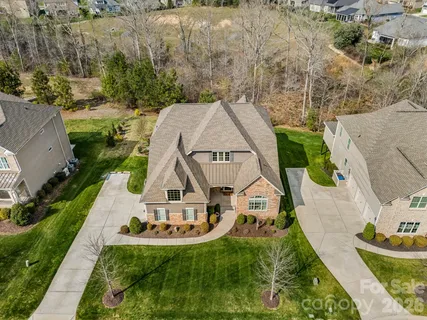 an aerial view of a house with swimming pool and large trees