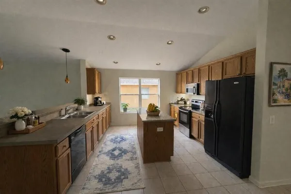 a kitchen with granite countertop a refrigerator stove and sink