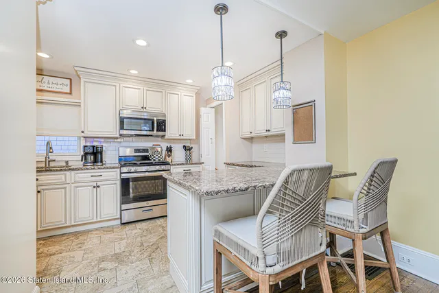 a kitchen with stainless steel appliances granite countertop a sink dishwasher a stove a microwave oven a refrigerator with island and chairs