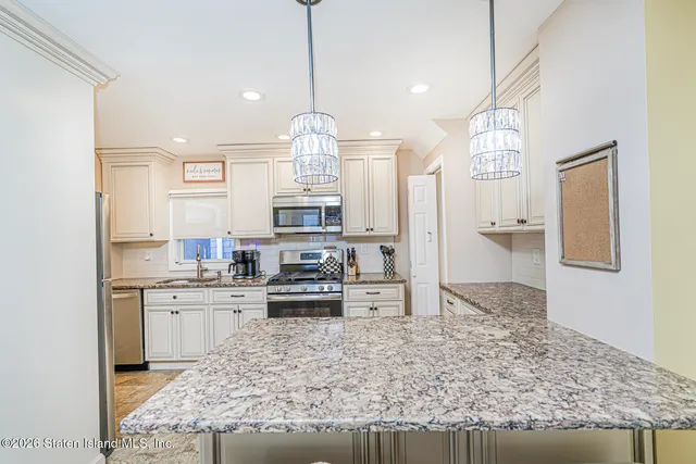 a large kitchen with stainless steel appliances kitchen island granite countertop a refrigerator oven a sink and dishwasher